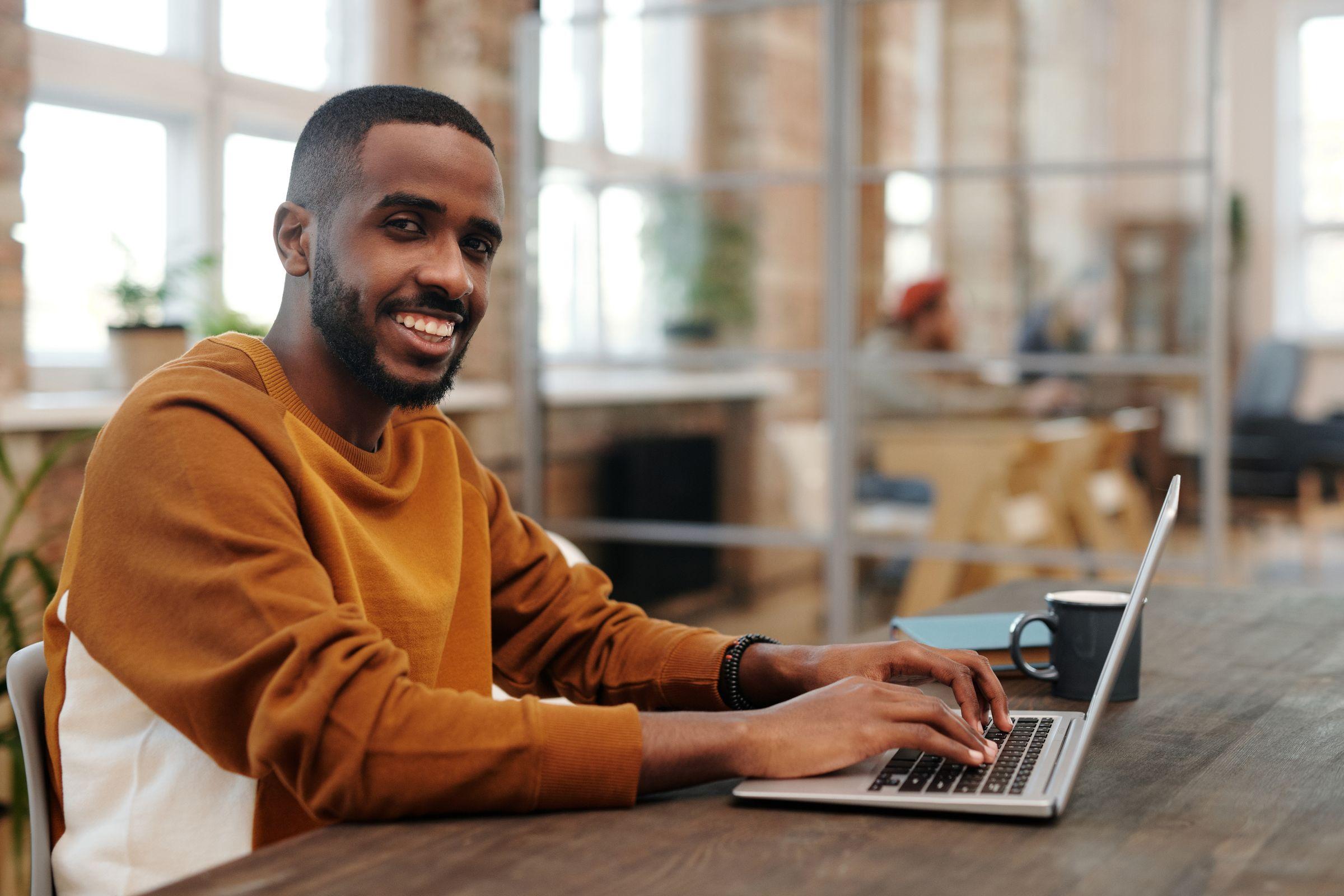 Smiling man typing on a laptop in a bright workspace